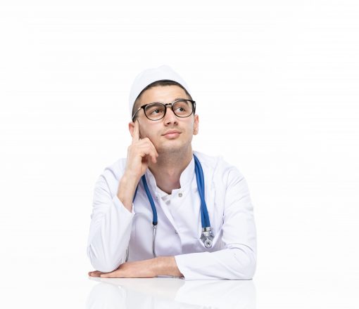 jovem-medico-de-terno-sentado-atras-de-uma-mesa-vista-frontal jovem-medico-de-terno-sentado-atras-de-uma-mesa-vista-frontal